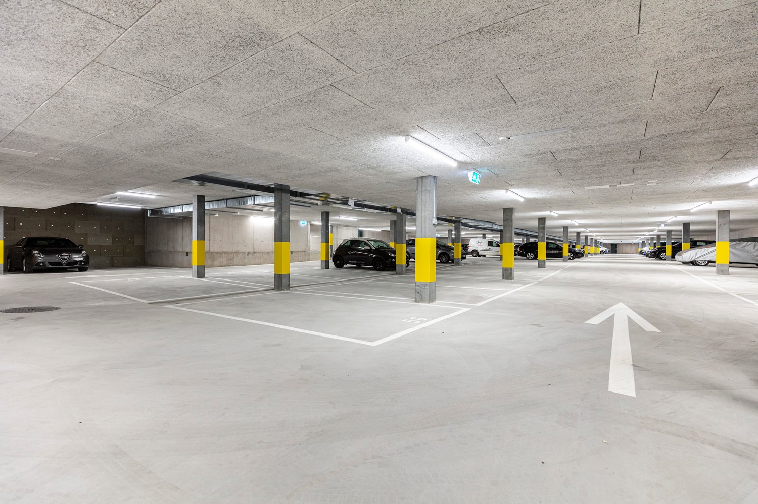 concrete floor, yellow pillars, multiple parking spots, white directional arrows