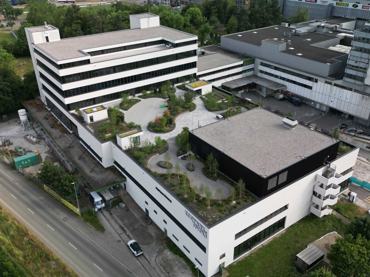 Multi-story office building with a landscaped courtyard, parking area, and surrounding greenery