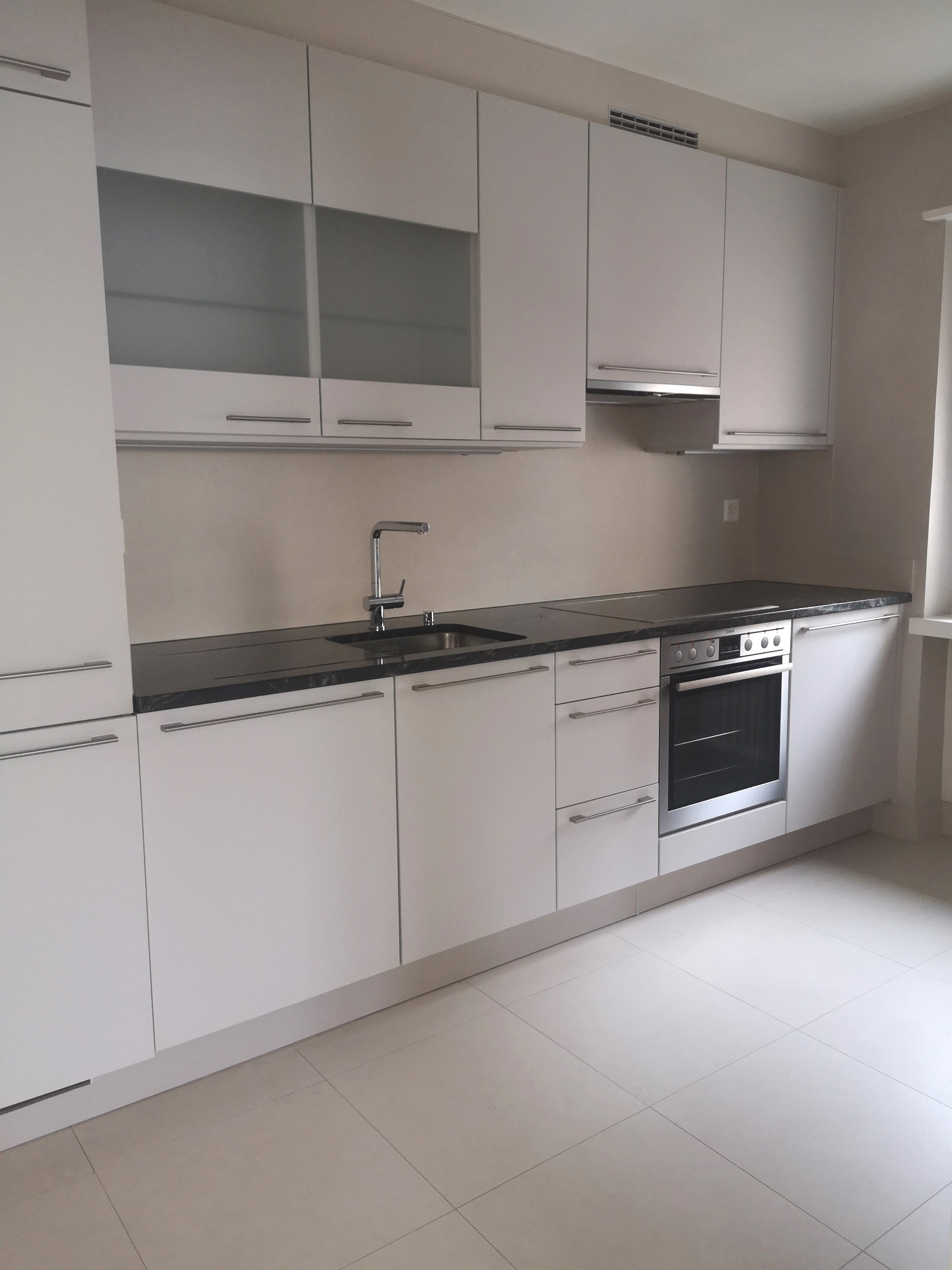 modern kitchen, white cabinets, black countertops, stainless steel appliances, marble floors
