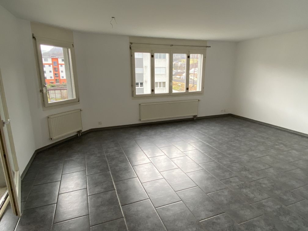 empty room, white walls, tiled floor, large windows, two white radiators