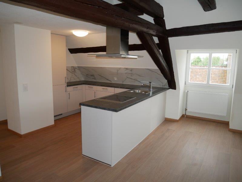 modern kitchen with a wooden floor and white marble countertops, white cabinets, silver metal stove hood and sink