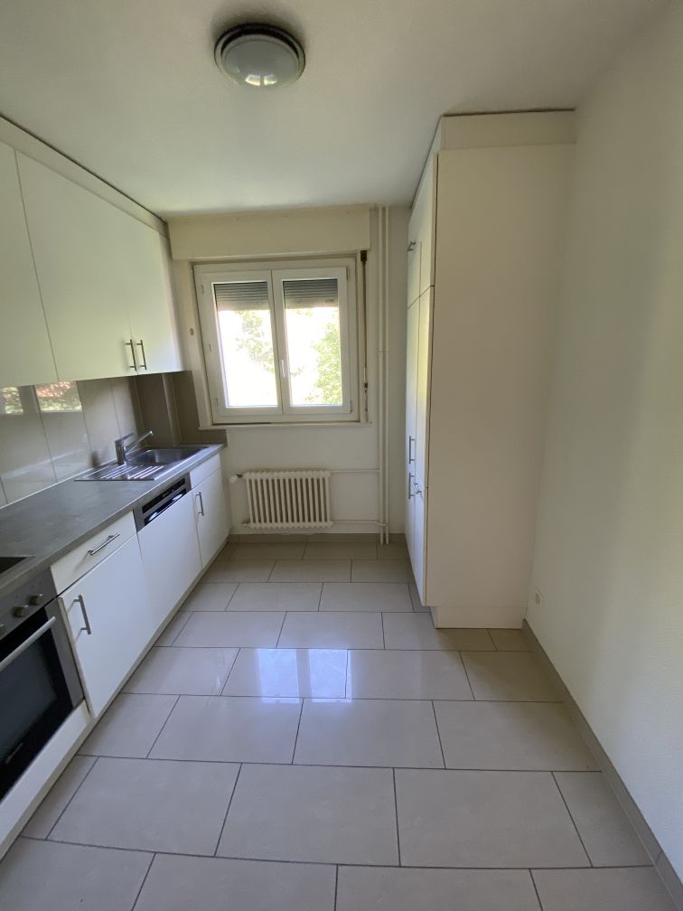 modern kitchen with white cabinets, tiled floor, sink, dishwasher, oven, window, radiator