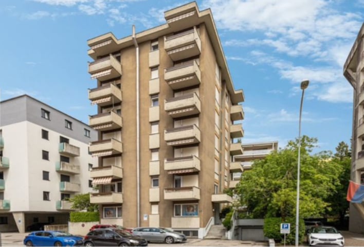7-story building, multiple balconies, multiple cars parked in front