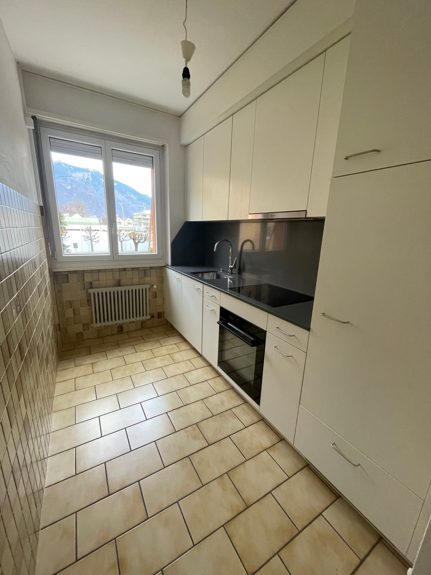 modern kitchen, tiled floor, white cabinets, black countertops, window with mountain view