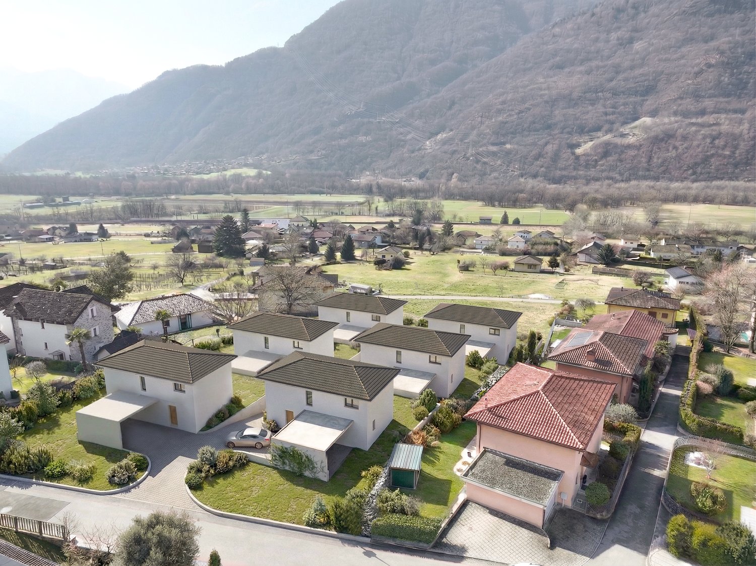 Cluster of modern houses, each with a garage, set in a green landscape with a mountain in the background