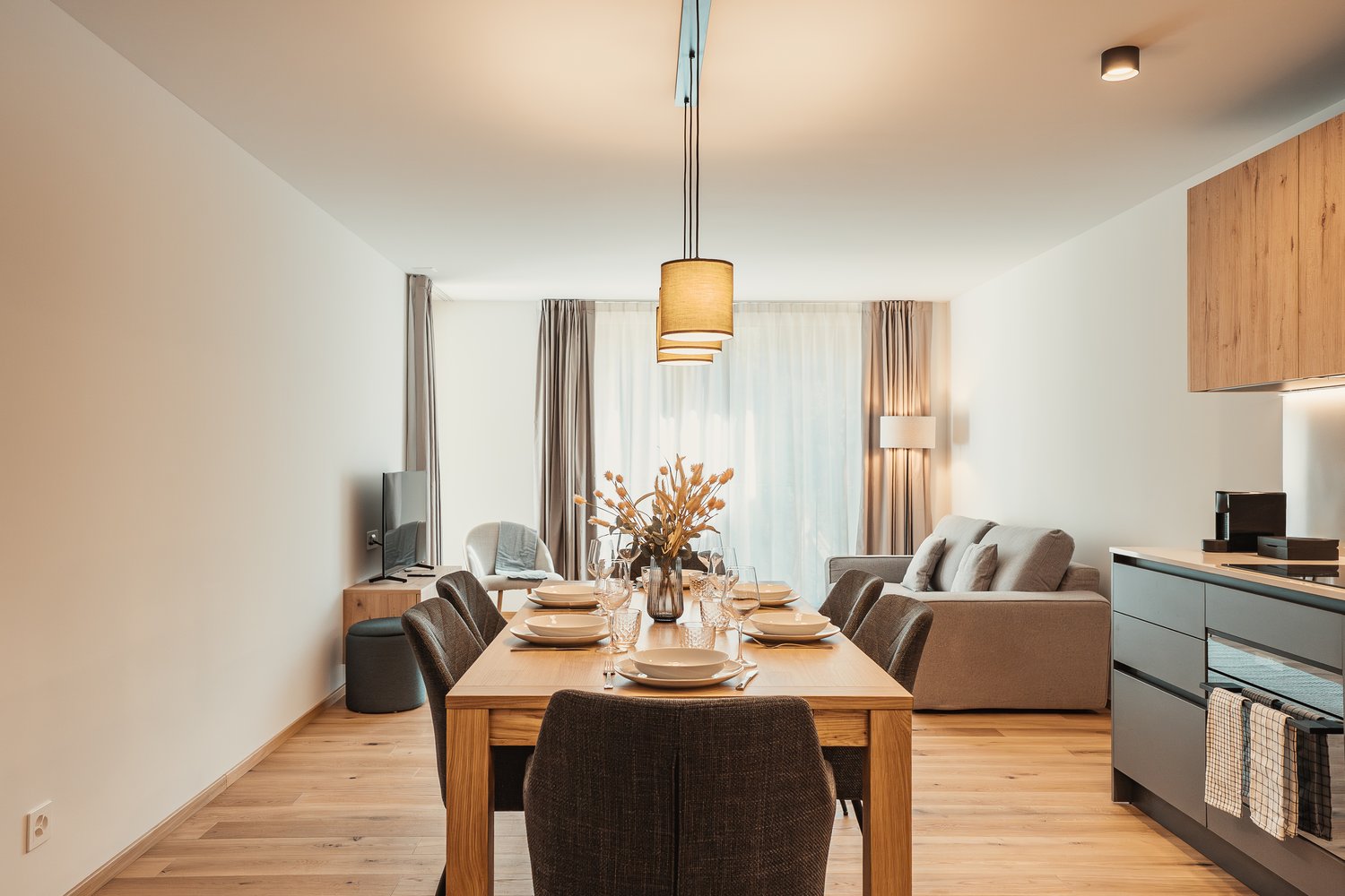 dining room with hardwood floors, large windows, dining table and chairs, sofa, TV, kitchen counter, cabinets, appliances