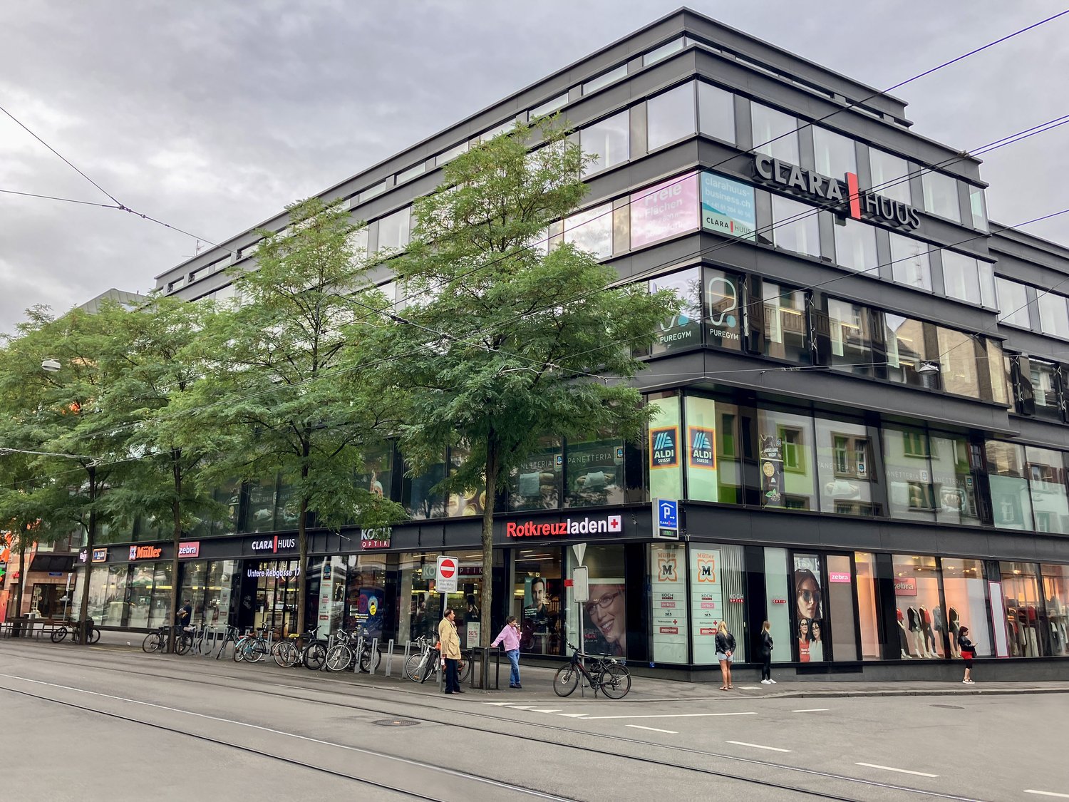 multi-story building, glass windows, parked bicycles, storefronts, pedestrians, urban setting