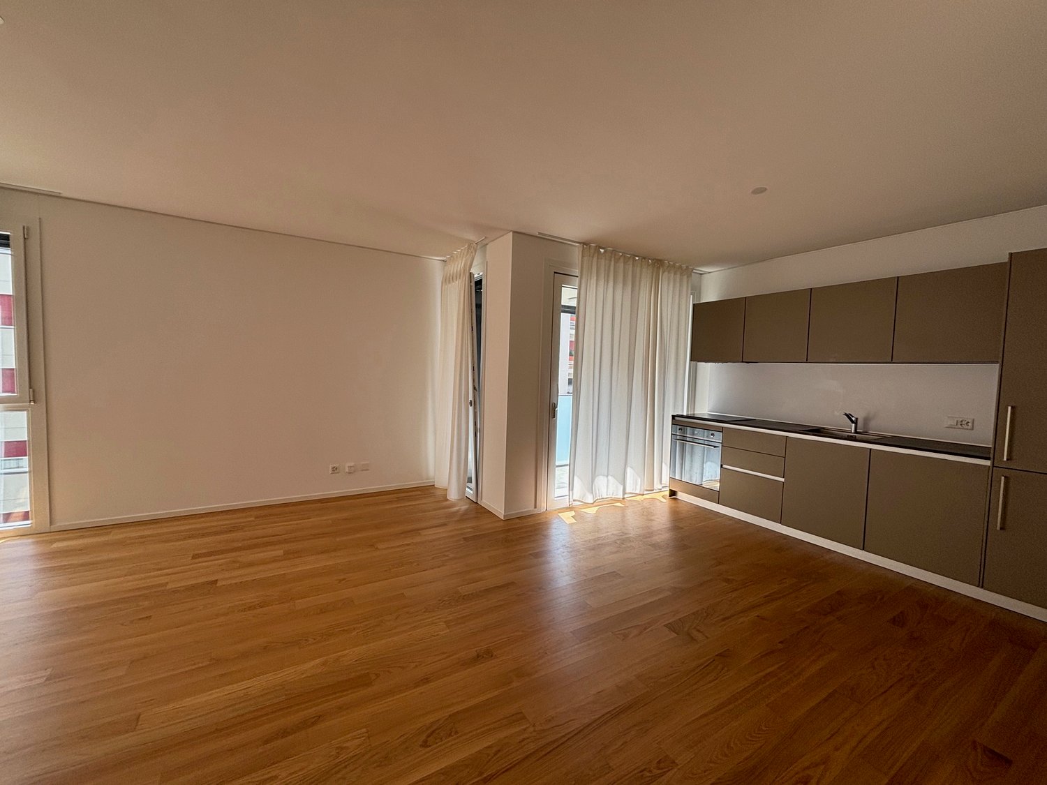 Open kitchen, hardwood floors, white walls, large windows, sliding doors, kitchen island, stainless steel appliances