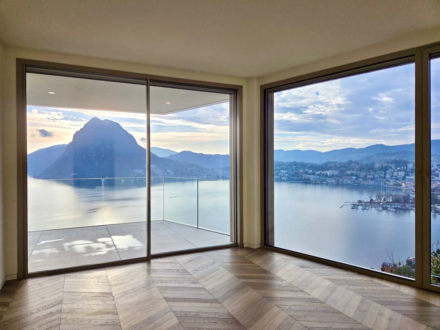 large floor to ceiling windows, wooden floor, balcony with glass railings