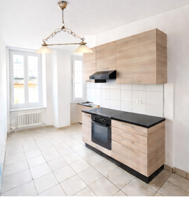 modern kitchen with white tiles, wooden cabinets, black countertops, chandelier, gas stove, oven, and built-in microwave, window with radiator