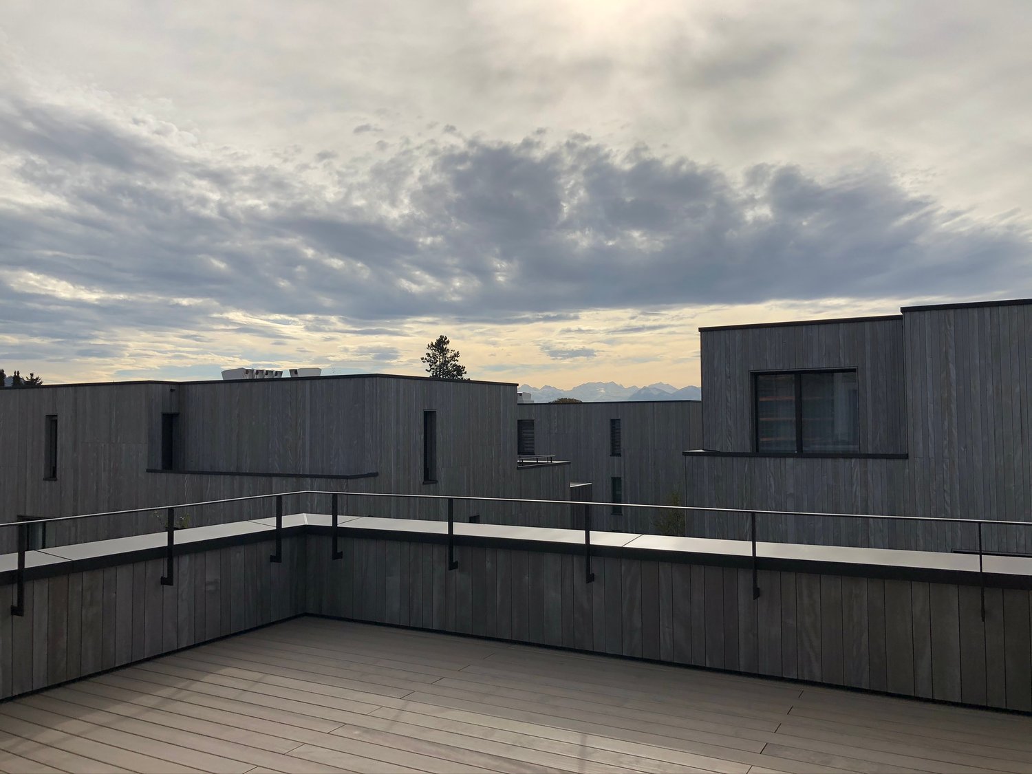 Rooftop terrace with wooden flooring, metal railings, and a view of the surrounding area
