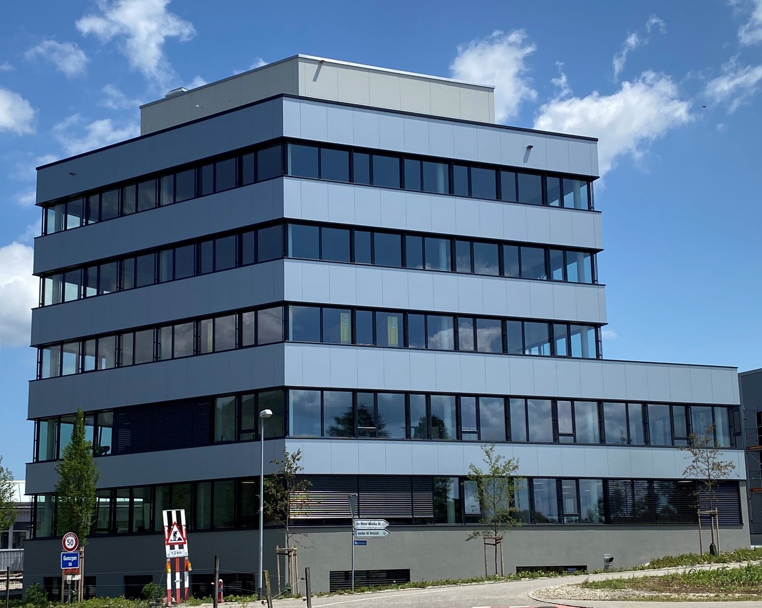 Modern office building with multiple floors, large glass windows, and a gray exterior.