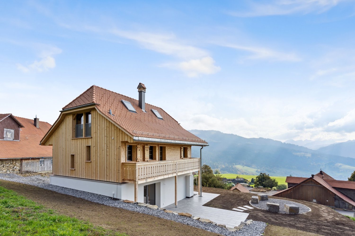 modern chalet style, wooden exterior, brown tiled roof, wooden balcony, chimney, multiple windows, raised ground