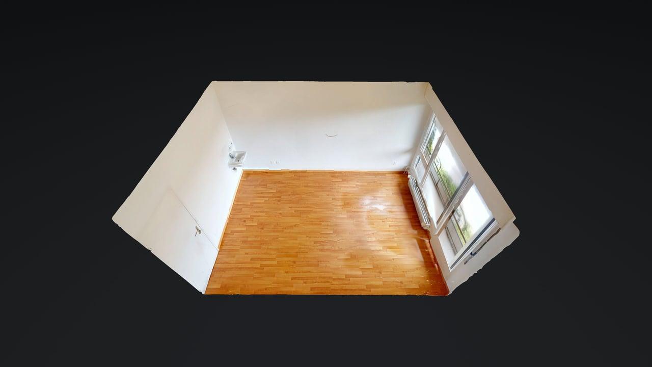 Empty room with wooden floor, white walls, and windows.