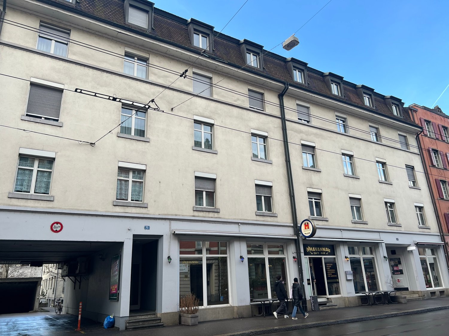 multistory building, large windows, ground floor commercial space, several people walking