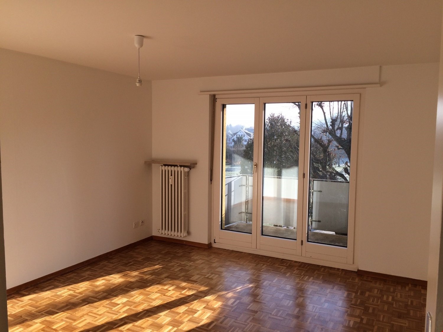 empty room, wooden floor, white walls, sliding glass doors, balcony, radiator