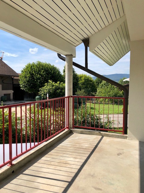 concrete floor, red metal railing, view of the yard and mountain