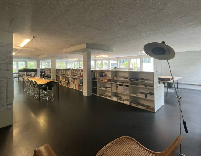 Library with bookshelves, tables, chairs, and a lamp.