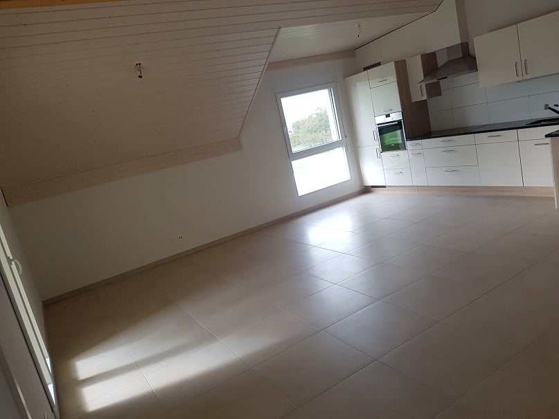 empty room with tiled floor, white walls, kitchen area with window, built-in appliances