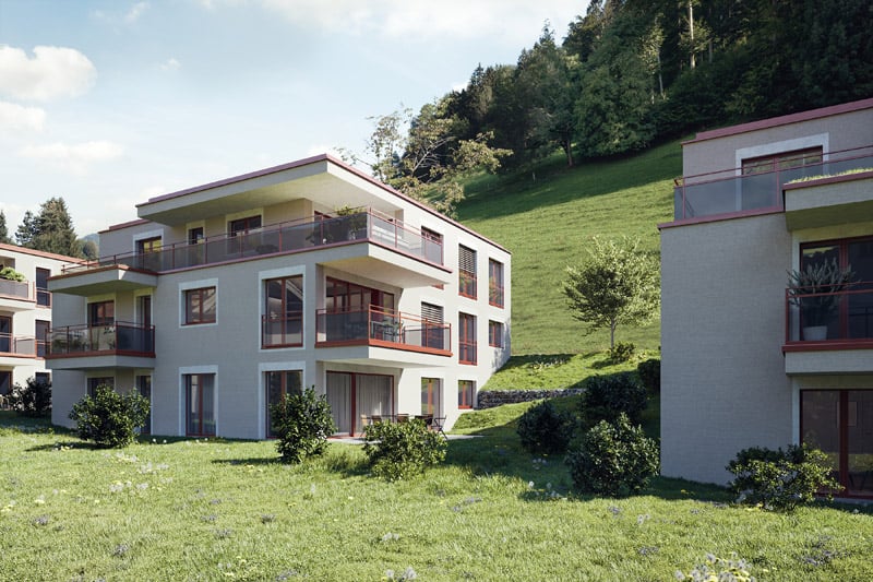 Apartment building with two floors, balconies, on a hillside with a view of the mountains, surrounded by greenery and a large lawn