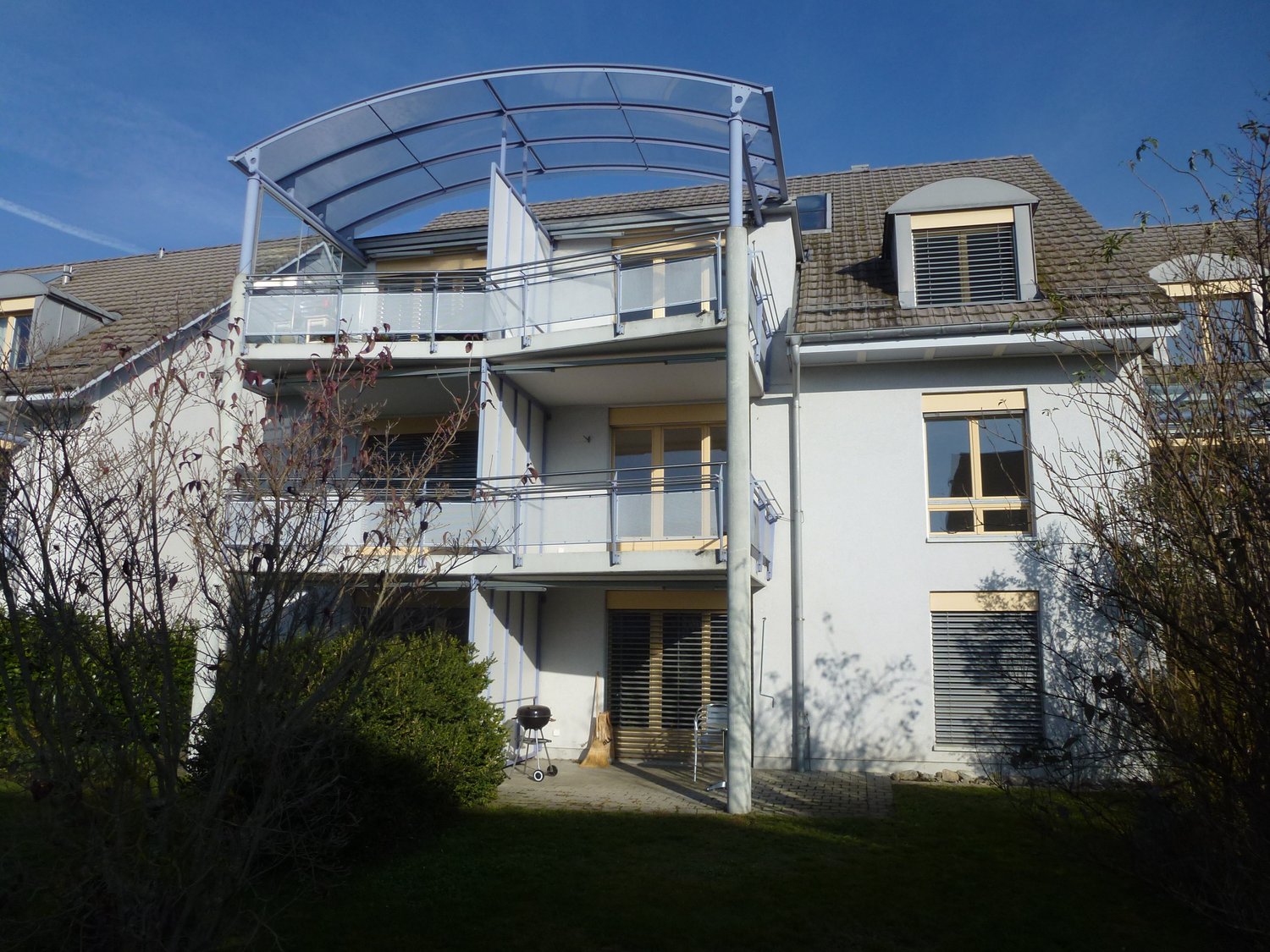 white 2 story building, with balconies, metal railings, entrance on the ground floor