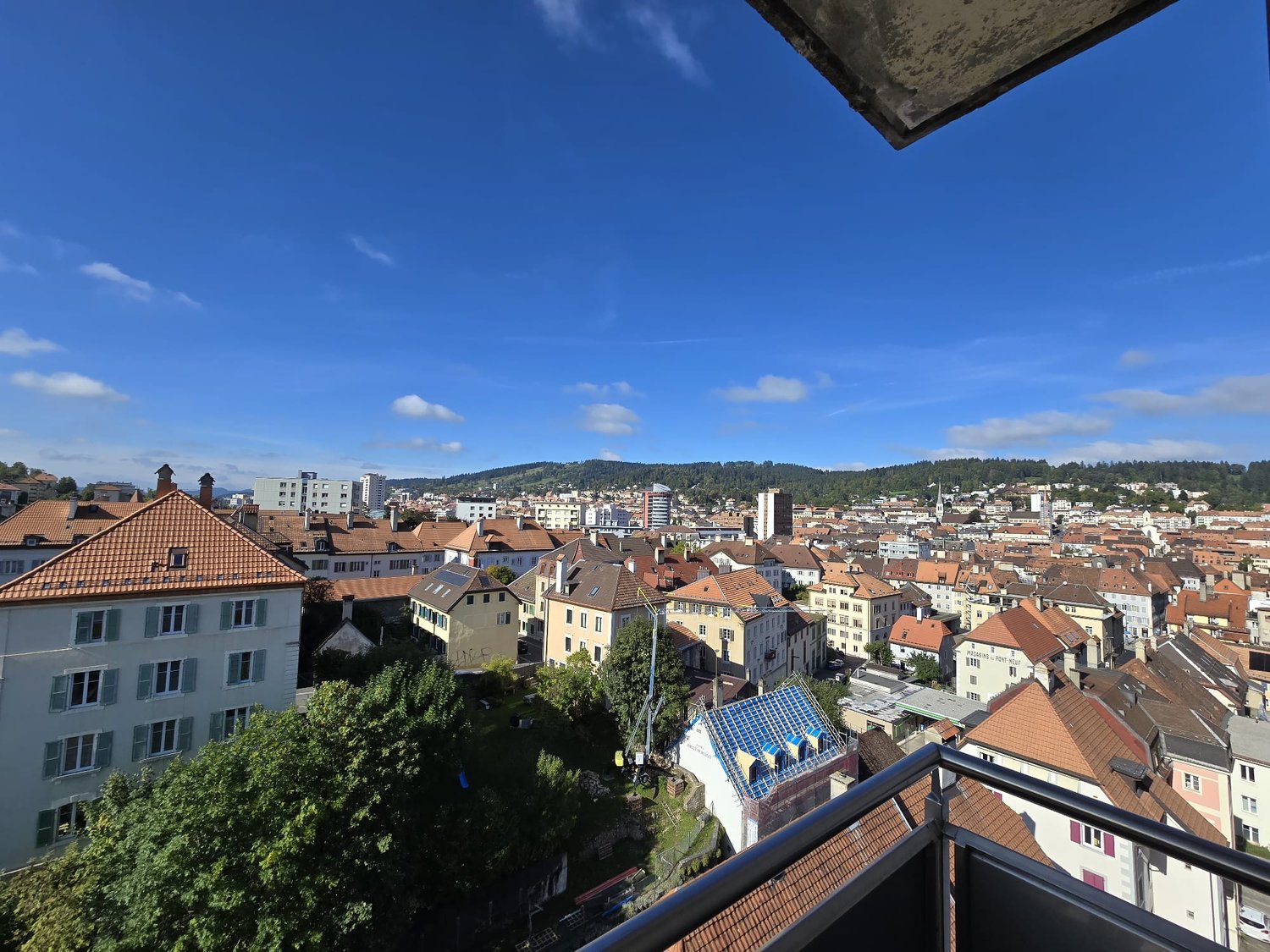 panoramic city view, buildings, hills, greenery, balconies