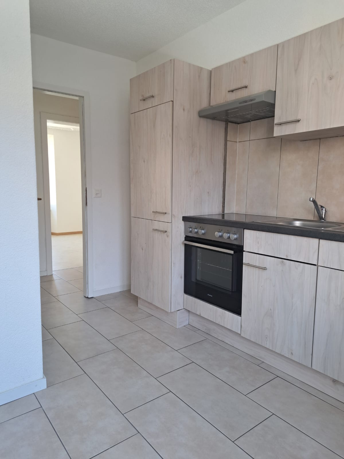modern kitchen with white tiled floor, wooden cabinets, stainless steel appliances, and a sink with a faucet