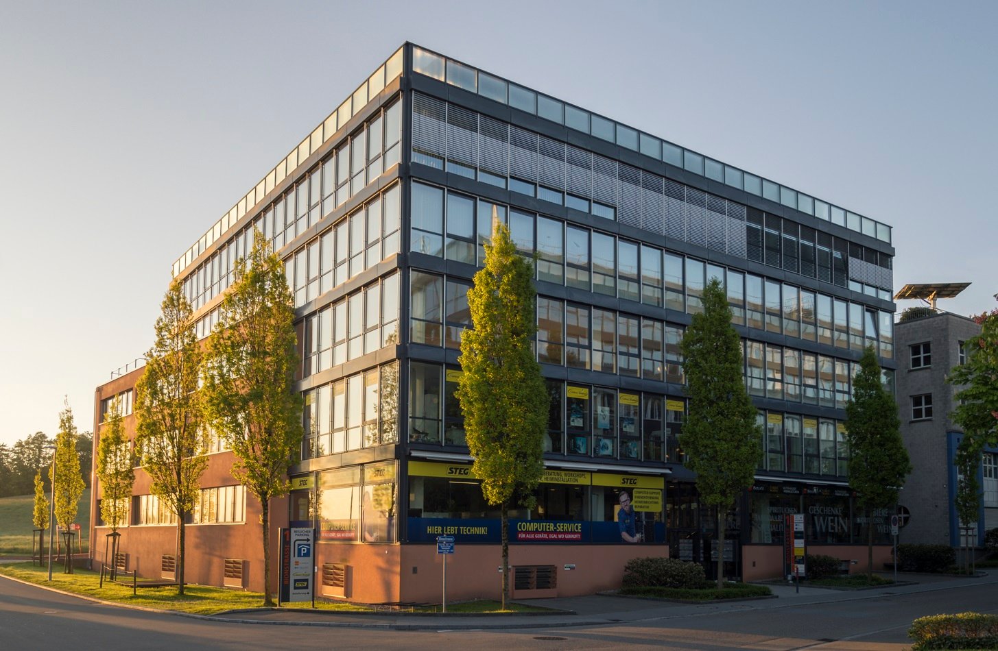 commercial building with glass facade, office, commercial signs, green trees, parking space