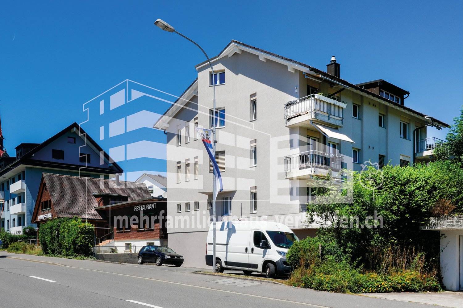 3 story building, white exterior, multiple balconies, street light, parked van, parked car