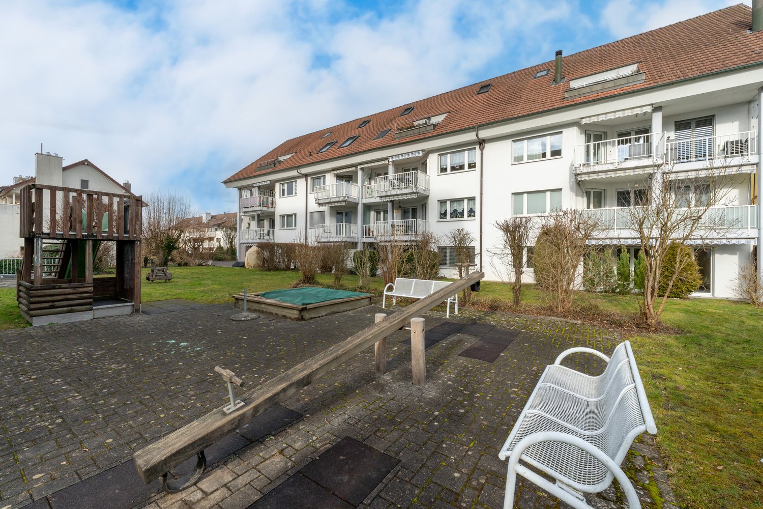 Large garden with play area, two benches, grassy area, and a covered pit for jumping