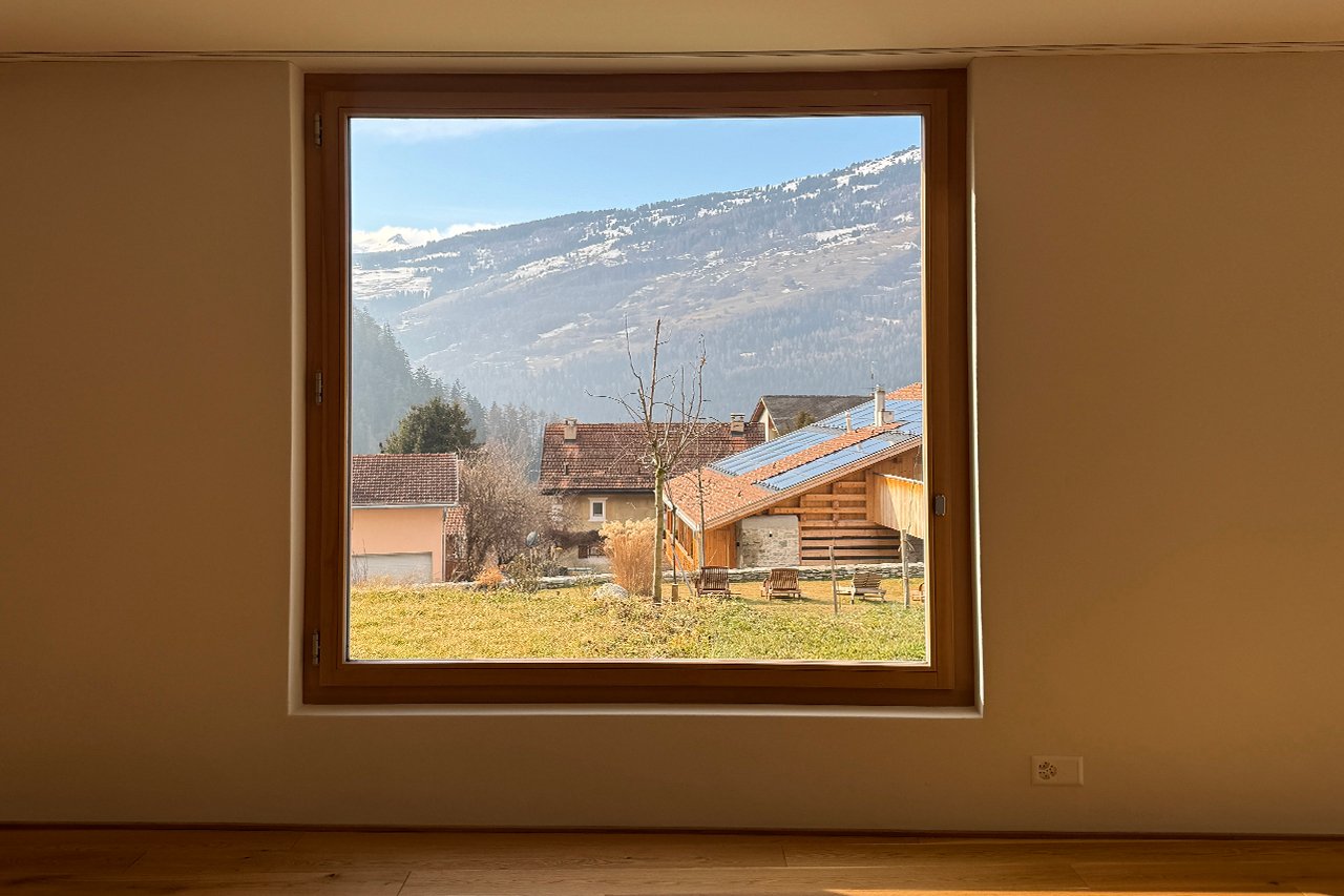 large window with view of mountains and houses