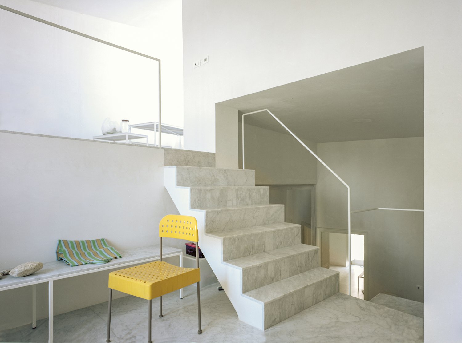 White marble stairs, yellow chair, stone countertop, marble flooring, modern design