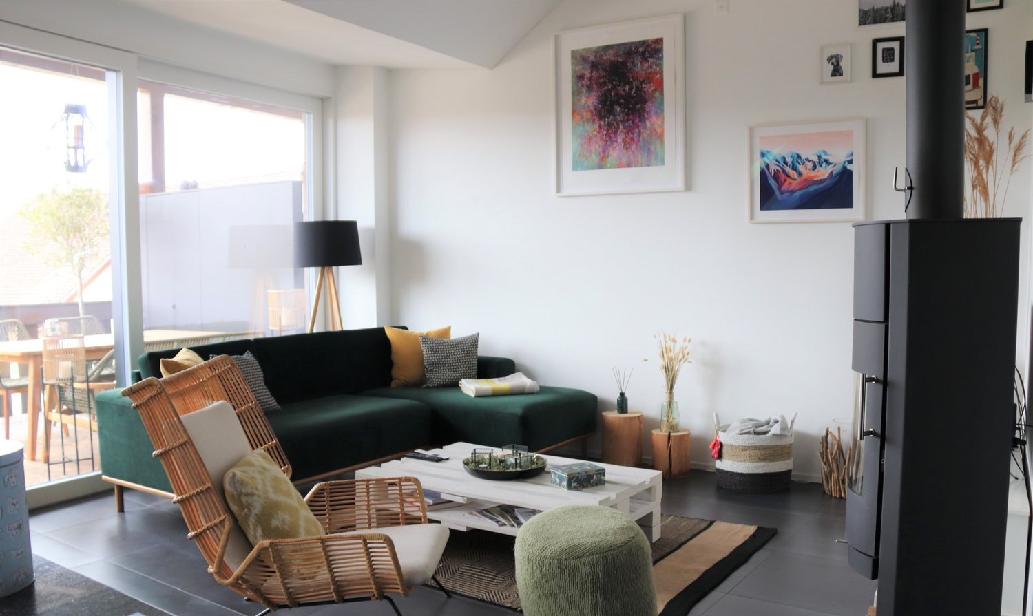 Living room with green sofa, coffee table, wooden chair, lamp, fireplace, and large windows