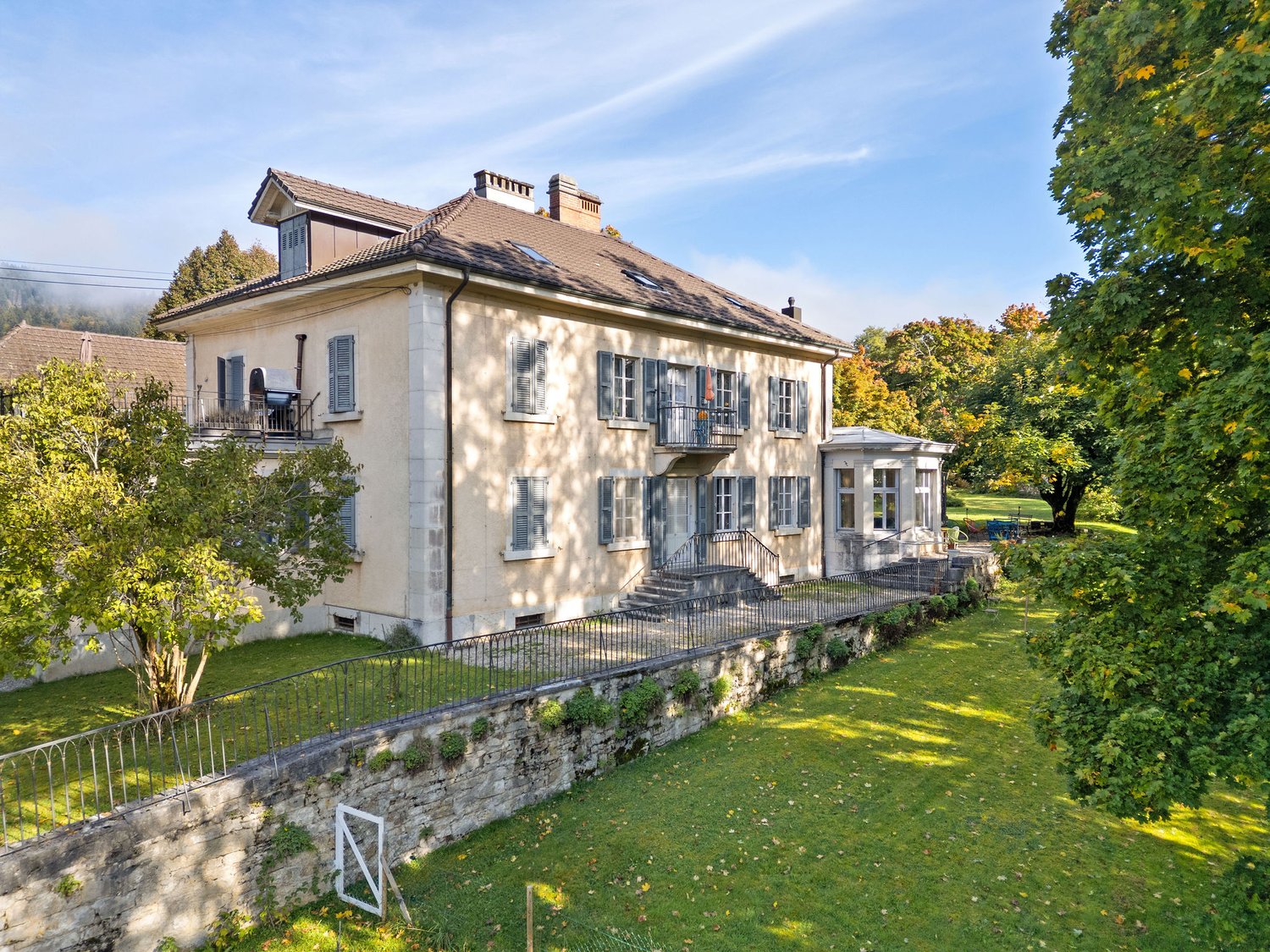 two-story house, beige facade, gray roof, balcony, large lawn in front, trees