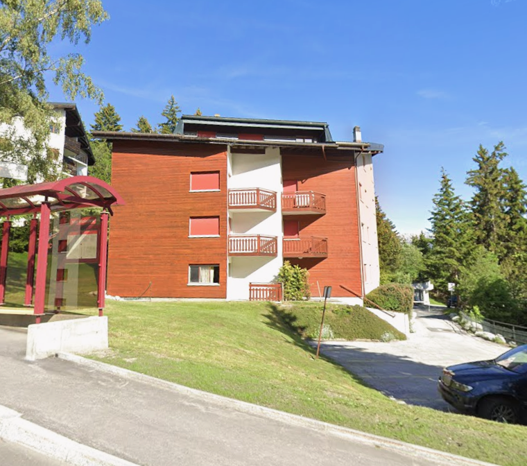 wooden and white building, 4 stories, balcony on each floor, tree-lined surroundings