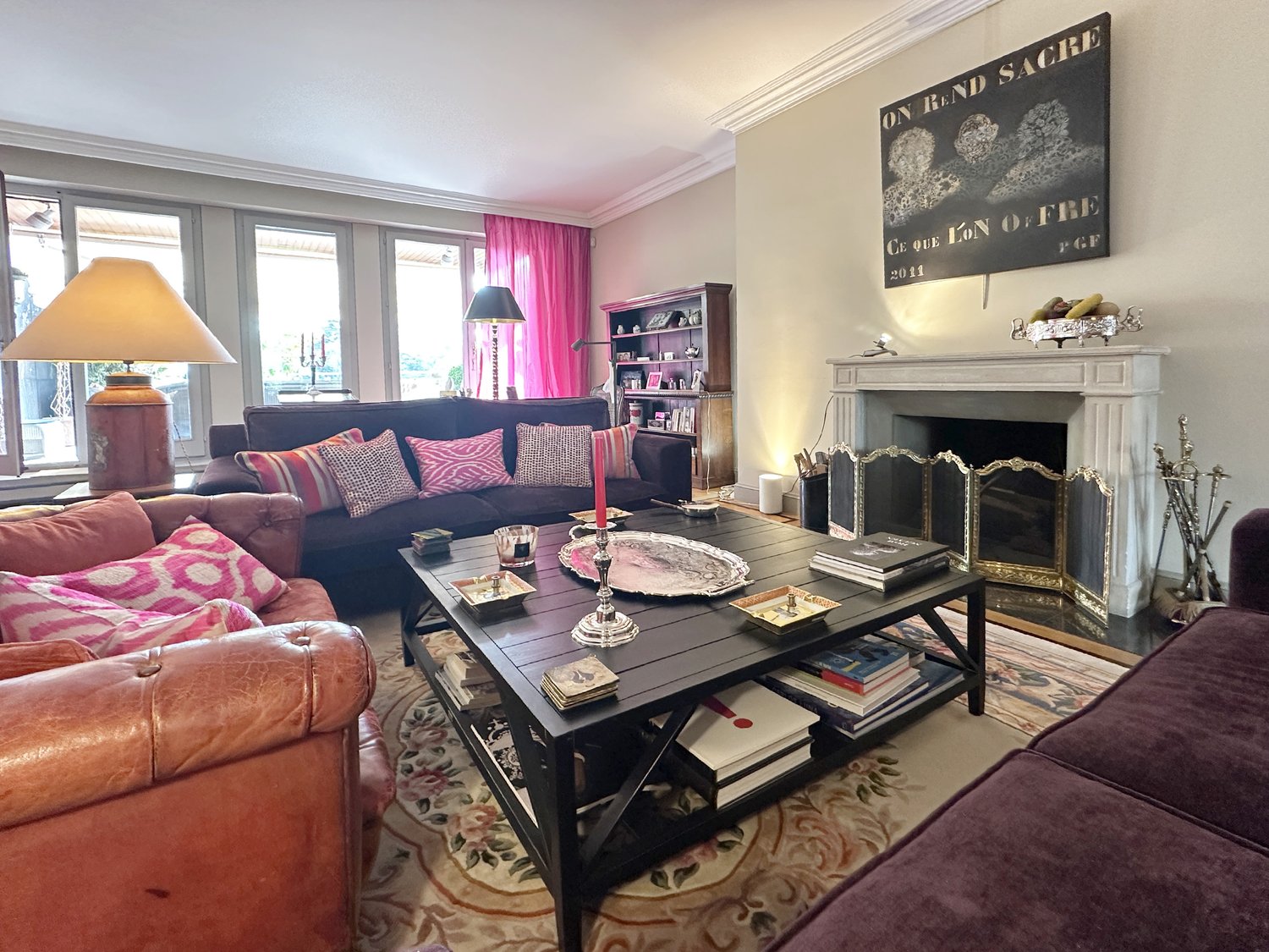 Living room with fireplace, bookshelves, coffee table, couches, lamps, and a rug