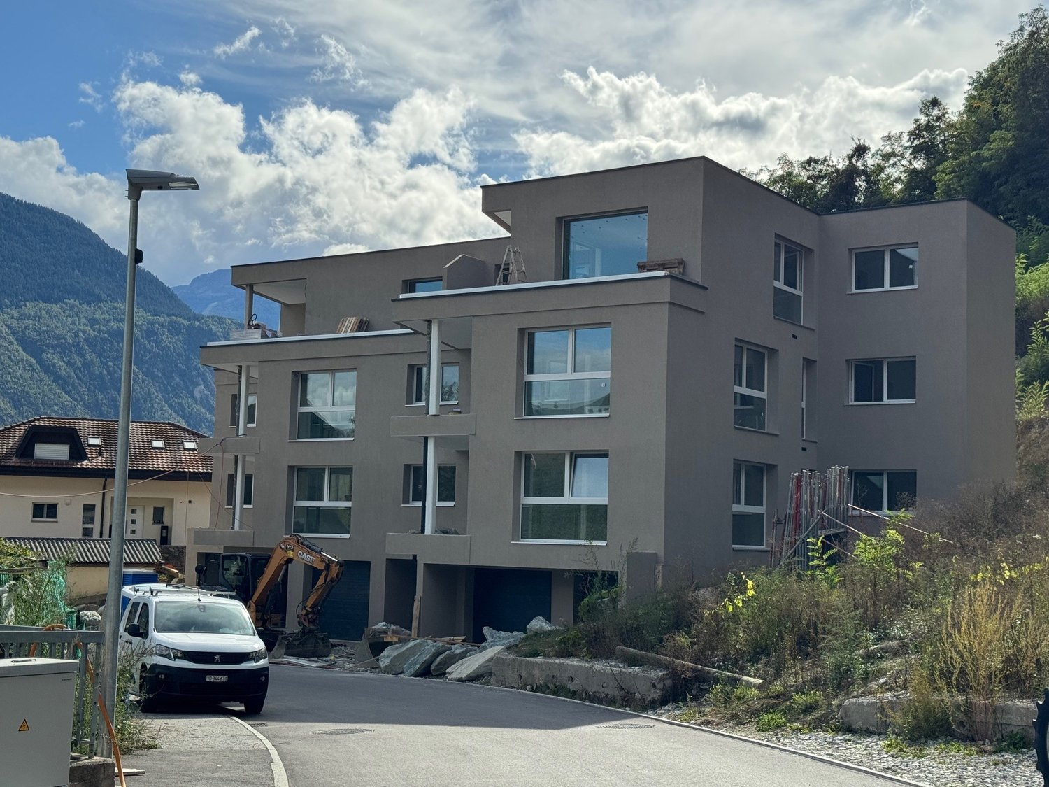 4-story building, concrete construction, large windows, open ground floor, mountain view