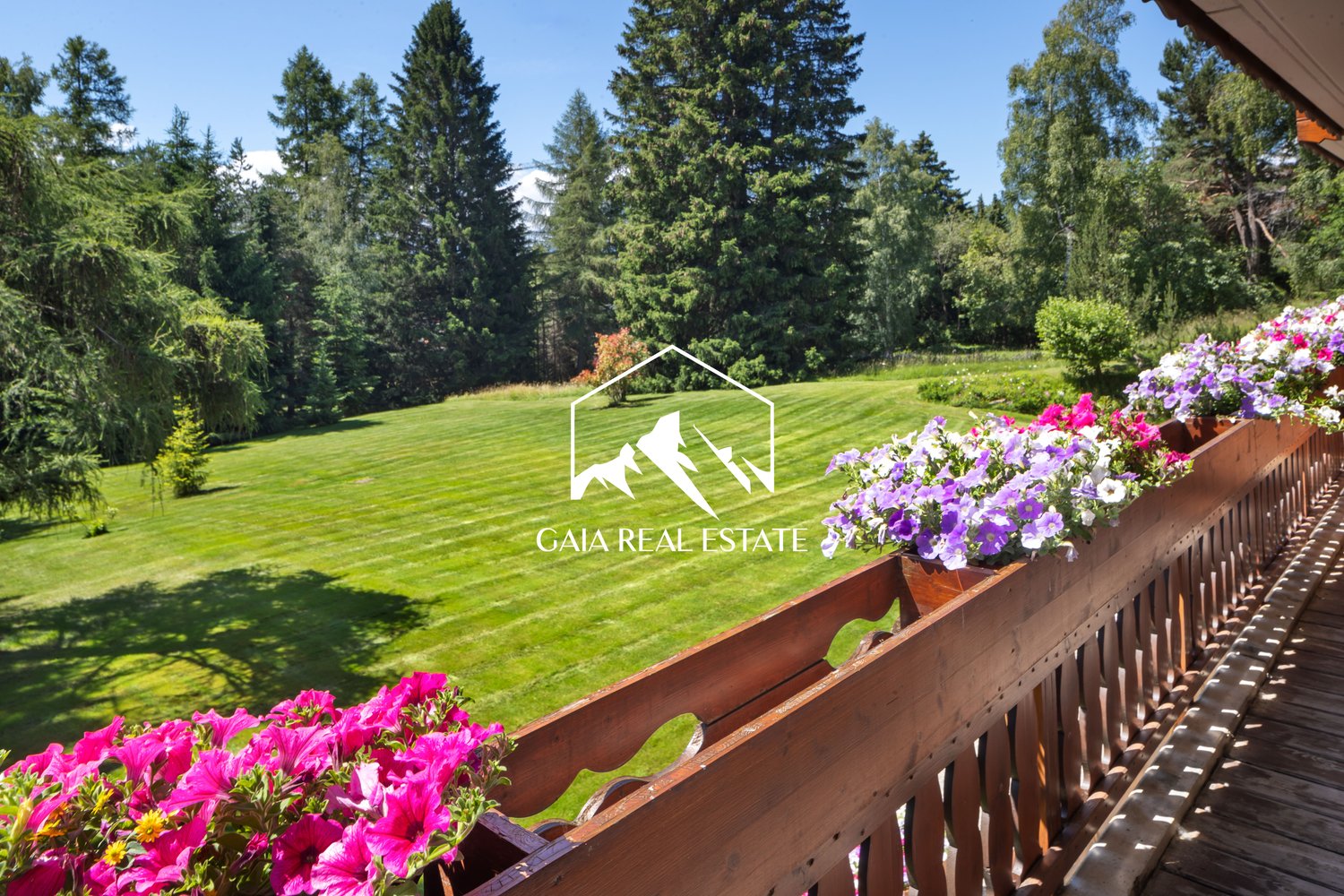 wooden balcony, lush lawn, purple and pink flowers, green trees, mountains