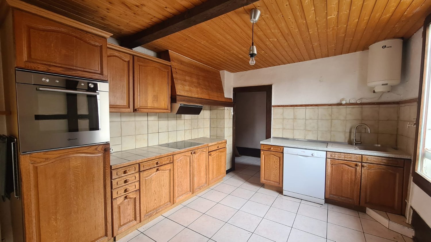 wooden cabinets, stainless steel oven, gas stove, wooden ceiling, white tiles, dishwasher