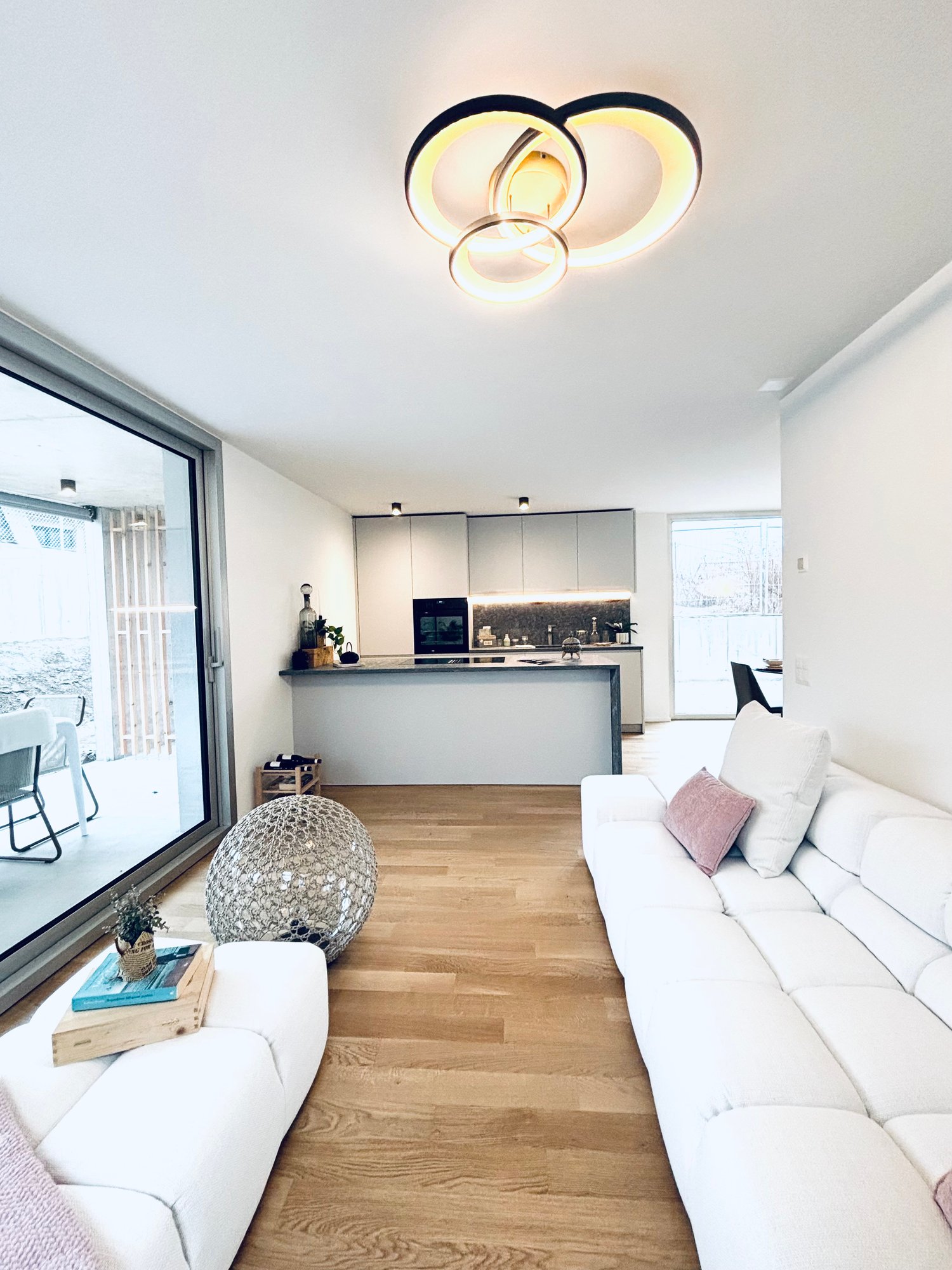 Open-plan living and kitchen area with modern decor and large windows