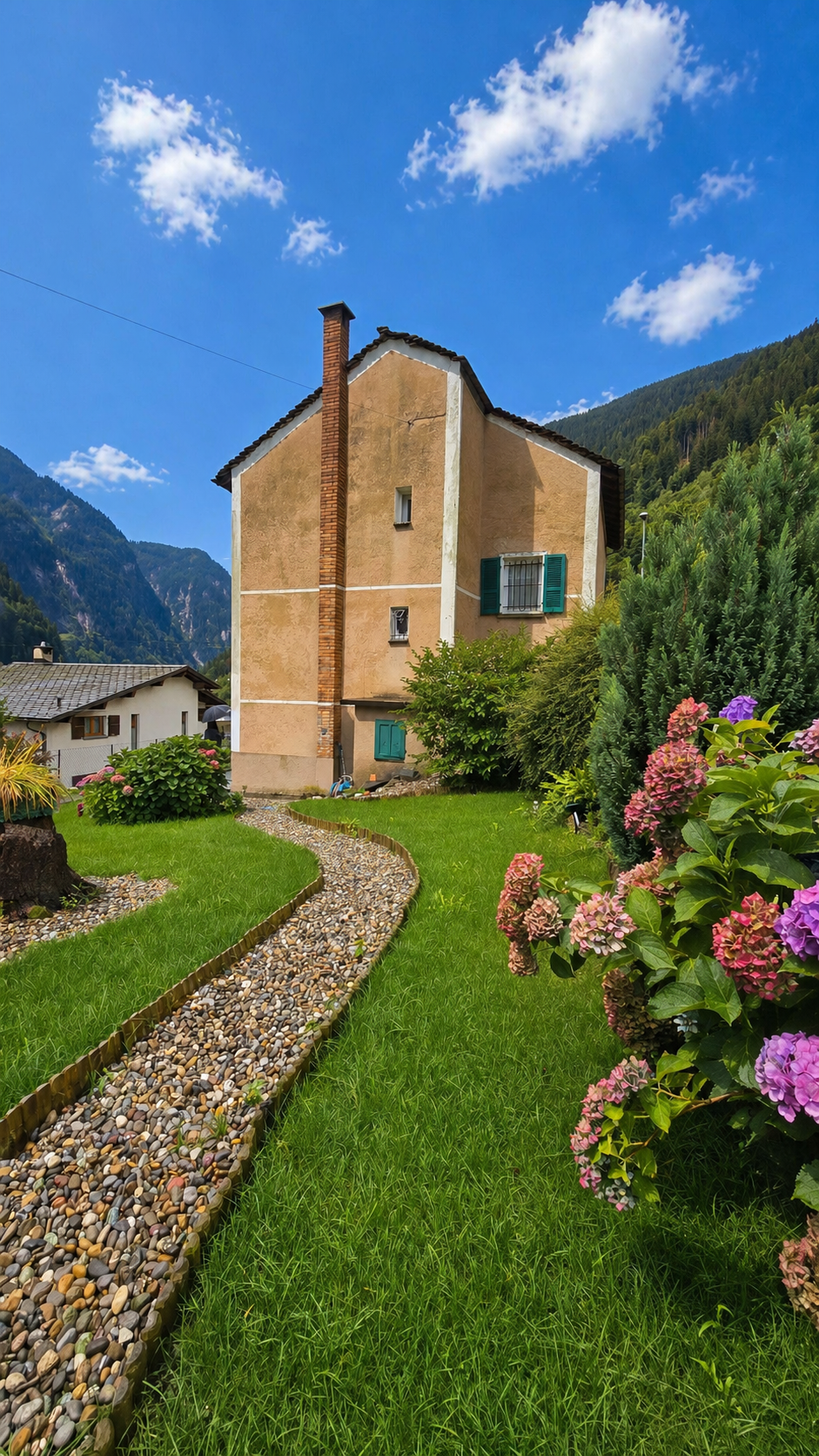 2 story house, brown brick, green shutters, garden, gravel path, mountain view