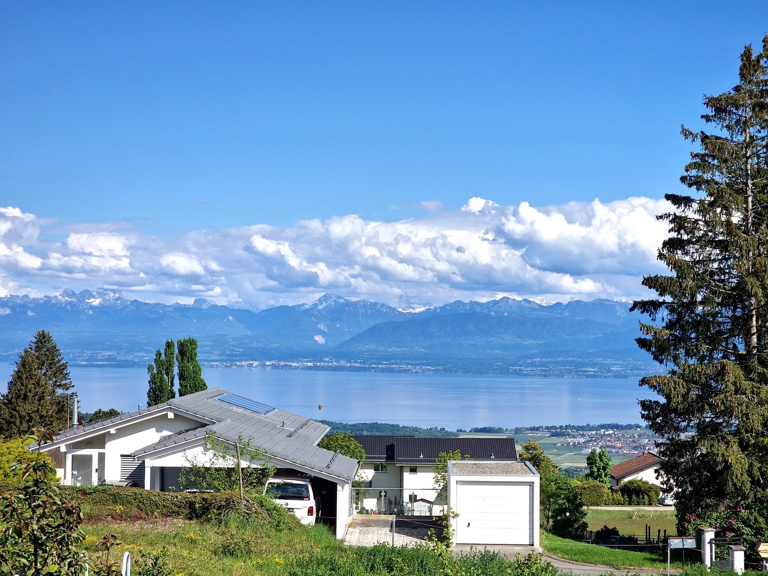 Detached house with solar panels, garage, and a view of the lake and mountains