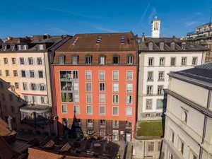 5 story building, red and white facade, many windows, balconies, green roof