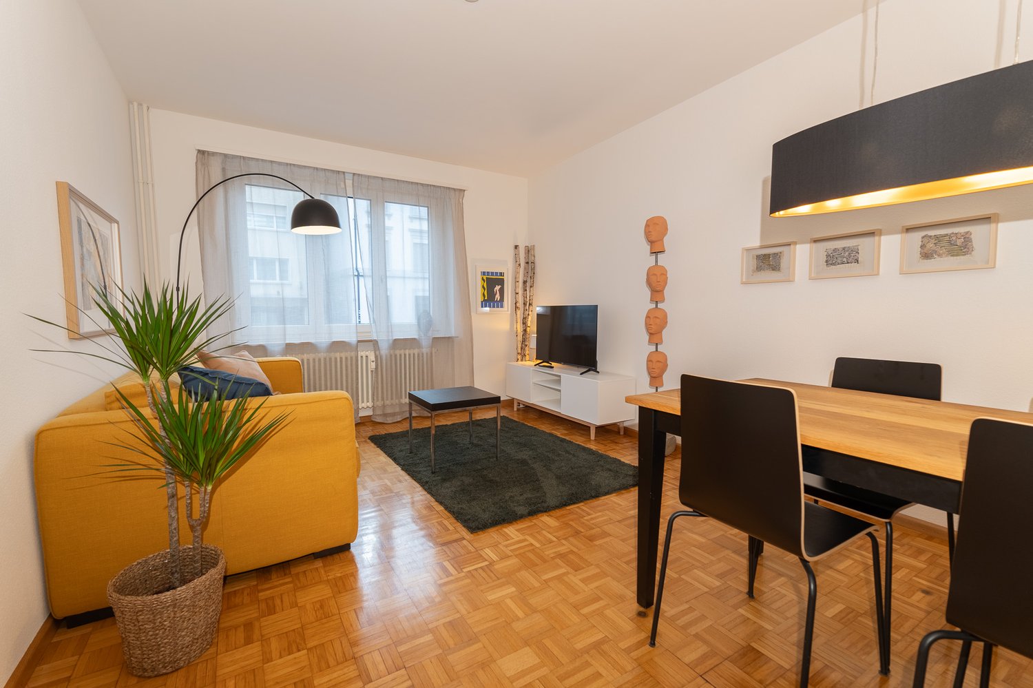 Wooden floor, yellow sofa, television, side table, dining table, floor lamp