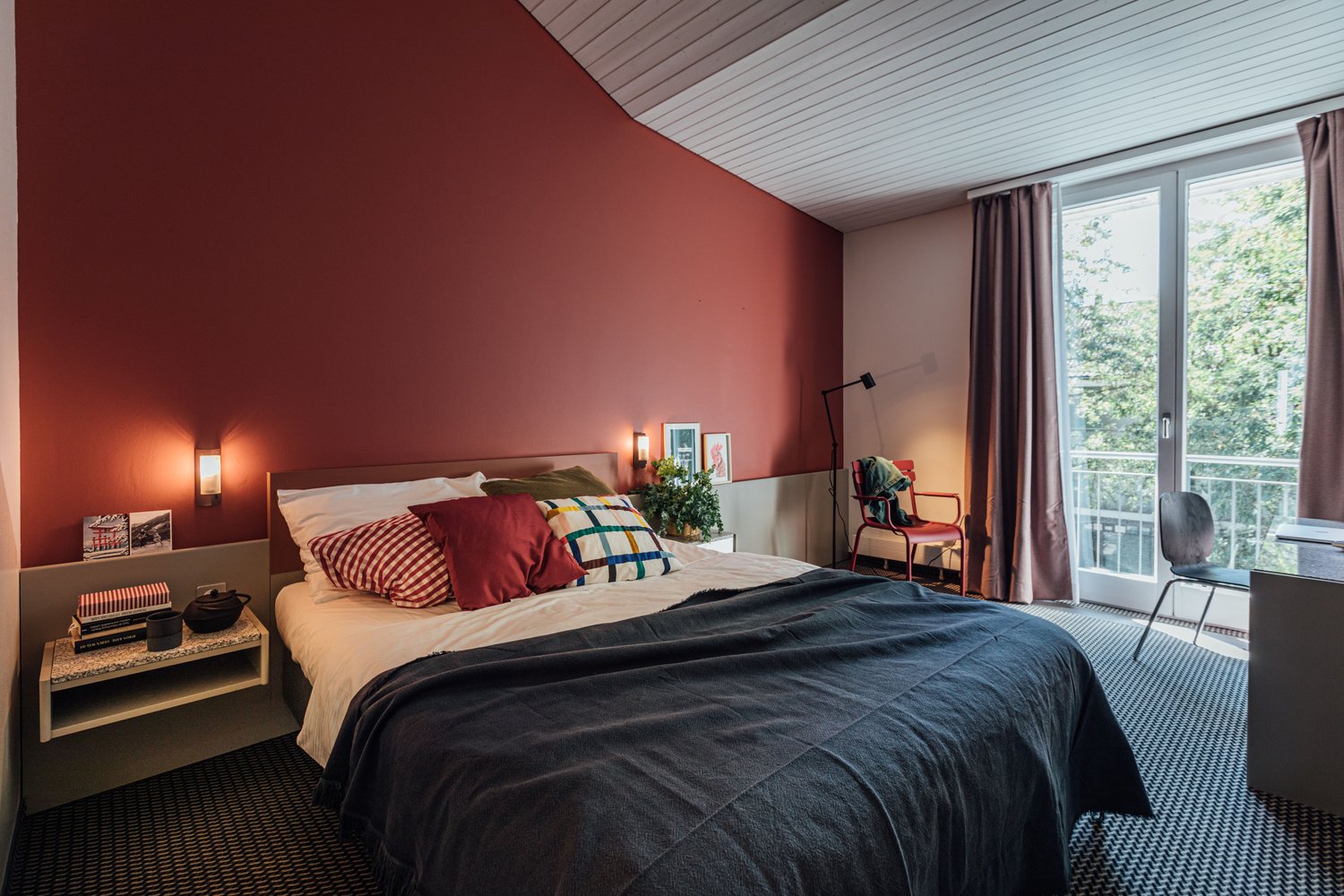 twin bed, bedside table, red wall, balcony, window, curtains
