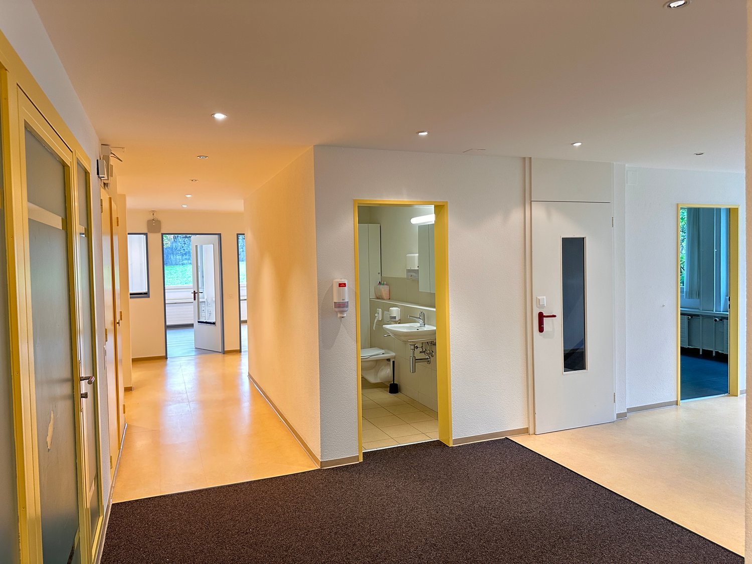Empty bathroom, bathroom door, sink, toilet, tiled floors, mirror, yellow accents
