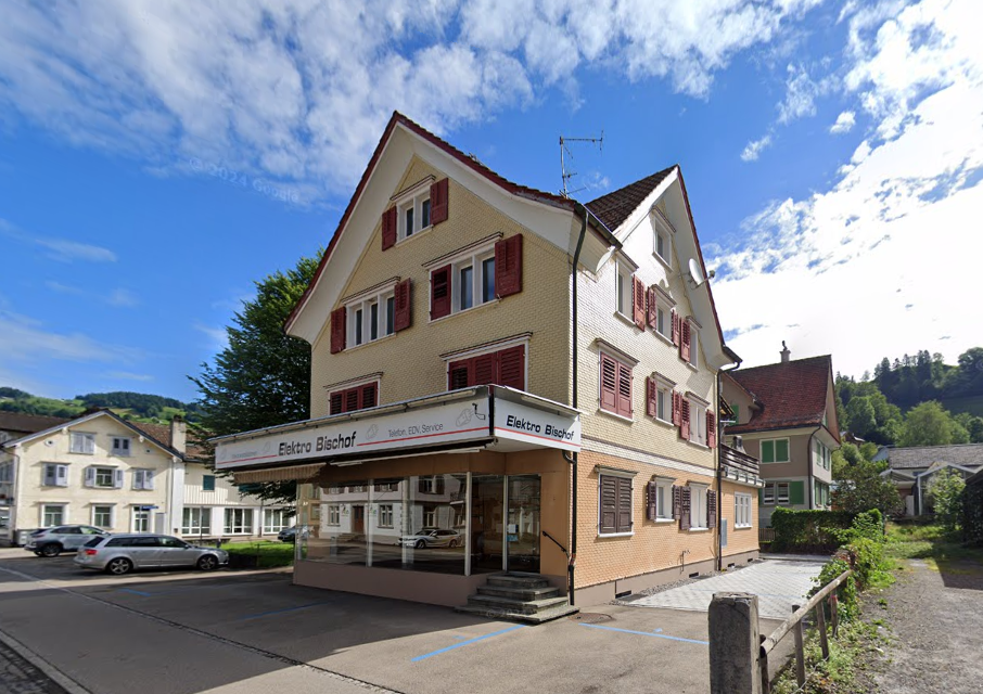 raised ground floor building, commercial use, multiple windows, slanted roof, red shutters, parking space