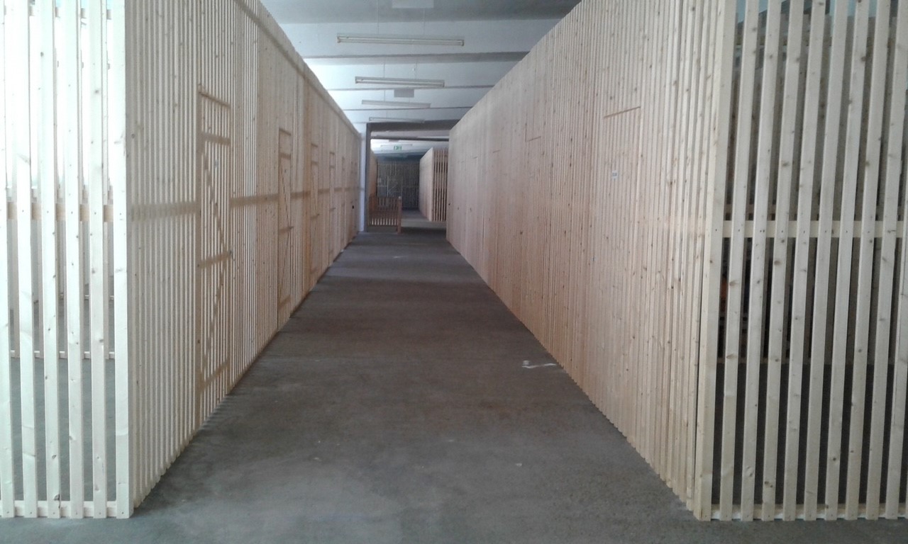 Concrete floor, white and light brown wooden walls, overhead lights