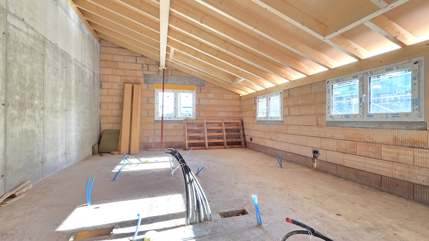 unfinished room, wooden beams, brick walls, three windows, electrical wires, wooden pallet