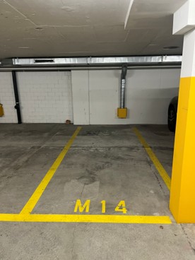The image shows a parking garage with a concrete floor, yellow parking space markings, and a parking space labeled 'M14'.